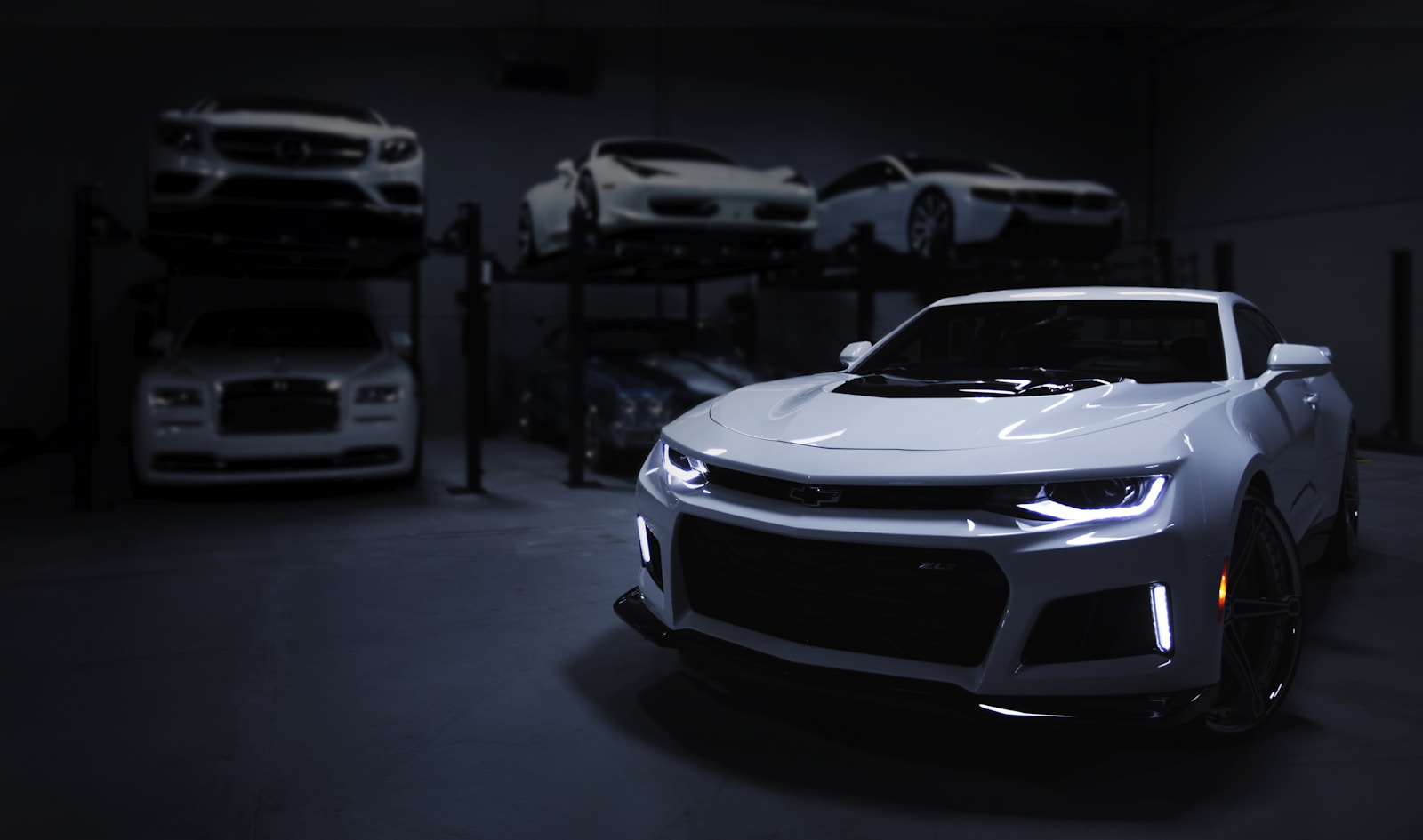 Vehicles parked under low light in a dealership storage bay
